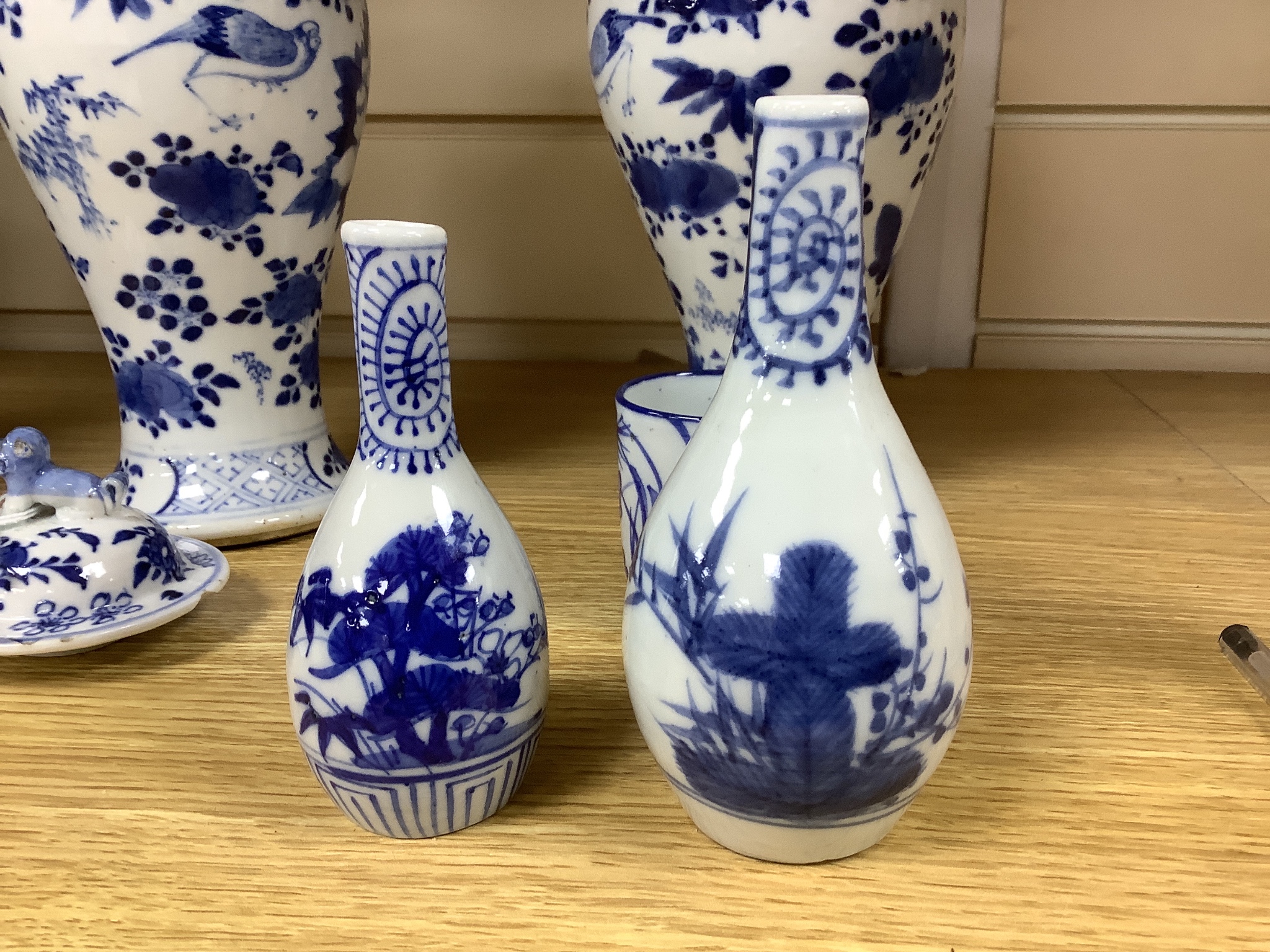 A pair of lidded Chinese blue and white vases, c.1900, Kangxi marks, 23cm high, together with two small Japanese vases, and a cup and saucer (6)